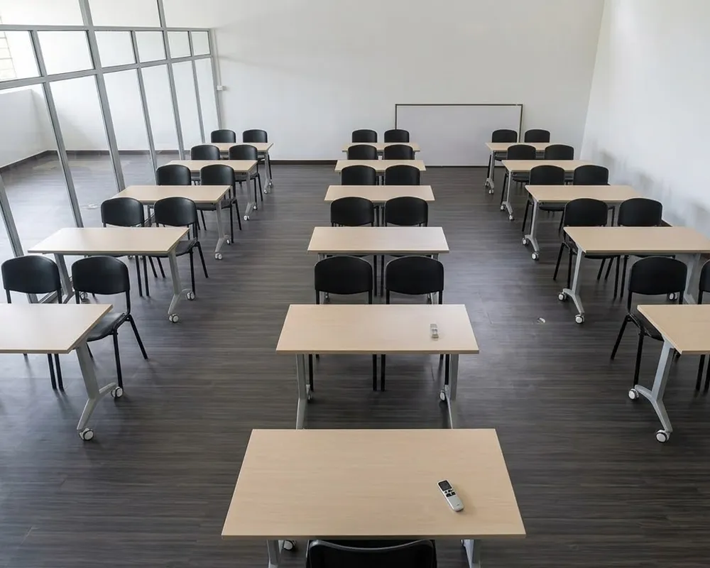 Salón de clase escolar moderno con filas de escritorios y sillas de madera vacías, representando mobiliario educativo en Colombia listo para los estudiantes.